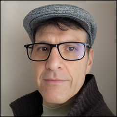 Portrait of a man wearing a gray flat cap and black glasses, looking at the camera with a neutral expression against a plain background.